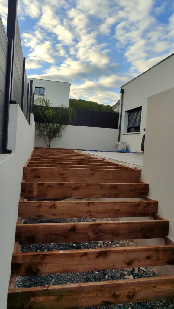Escalier Bois Extérieur : Chantier Terrasse Moderne Structure d'escalier extérieur en bois en construction entre deux maisons blanches modernes.